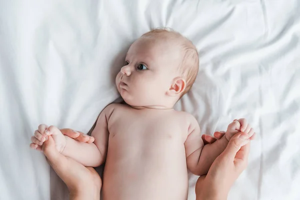 Вид сверху на мать, держащую за руки лежащую на кровати новорожденную дочь — стоковое фото