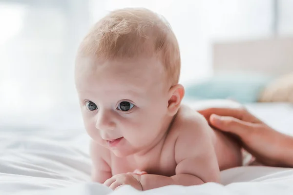 Cropped view of woman touching cute baby daughter lying on bed — Stock Photo