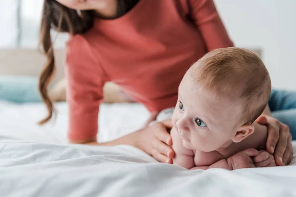 Vista ritagliata della donna che tocca il bambino sul letto a casa — Foto stock