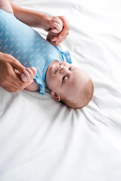 Ausgeschnittene Ansicht einer Frau, die Baby-Tochter in blauem Babybody berührt — Stockfoto