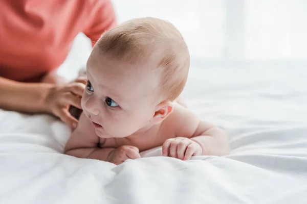 Ausgeschnittene Ansicht einer Frau, die ein Baby massiert, das zu Hause im Bett liegt — Stockfoto