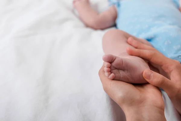 Cropped view of caring mother touching leg on infant baby — Stock Photo