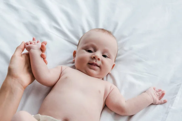 Vue de dessus de la main touchante de mère de bébé adorable fille regardant la caméra — Photo de stock