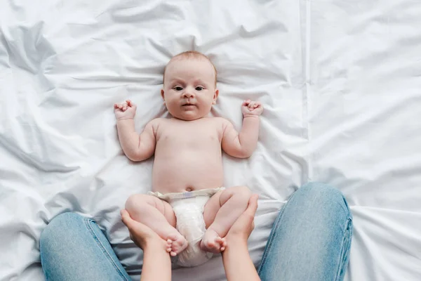 Abgeschnittene Ansicht von Mutter in Jeans, die entzückende kleine Tochter mit barfuß berührt — Stockfoto