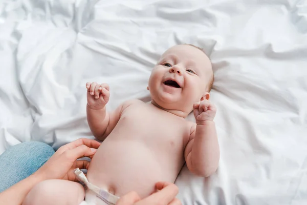 Recortado vista de la madre cosquillas alegre bebé hija en pañal - foto de stock