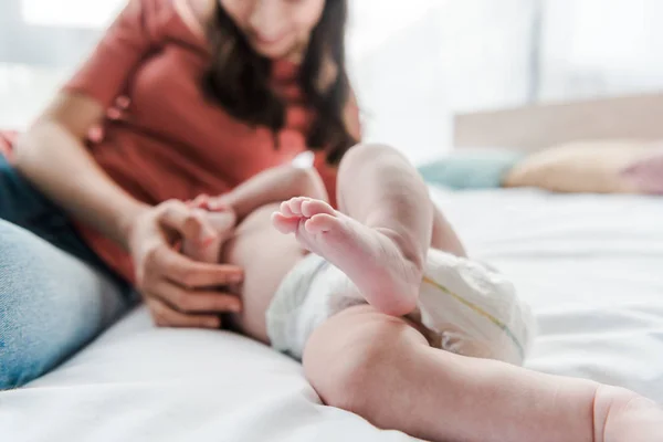 Selective focus of barefoot of cute infant near mother on bed — Stock Photo