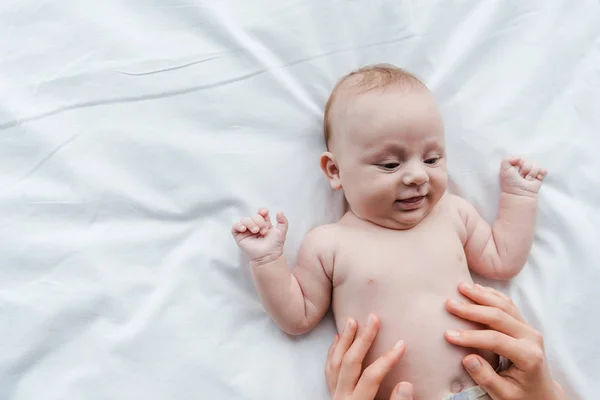Vue de dessus de la mère touchant fille bébé souriante sur le lit — Photo de stock