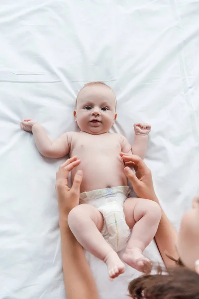 Ansicht von oben fürsorgliche Mutter berührt niedlichen Säugling Tochter auf dem Bett — Stockfoto