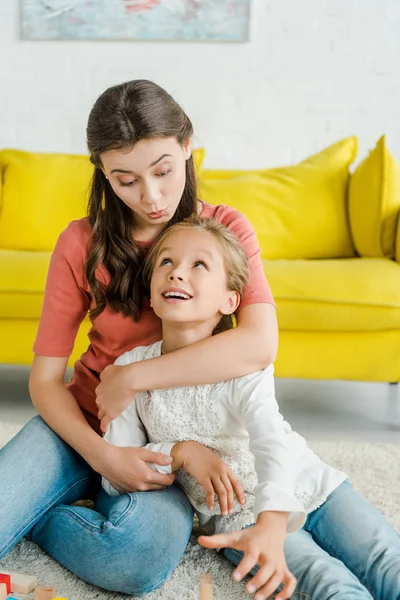 Attraktive Babysitterin schaut glückliches Kind im Wohnzimmer an — Stockfoto