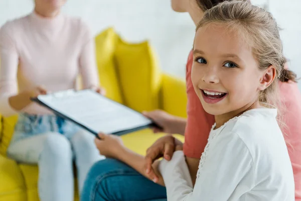 Foyer sélectif de l'enfant souriant près de la mère et baby-sitter à la maison — Photo de stock