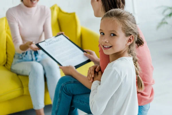 Selective focus of child smiling near mother and babysitter at home — Stock Photo