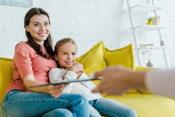 Happy babysitter sitting near happy kid and mother with clipboard — Stock Photo