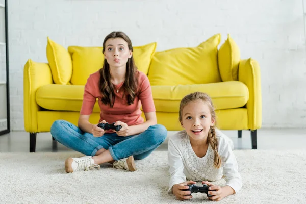 KYIV, UKRAINE - SEPTEMBER 4, 2019: babysitter and positive kid playing video game in living room — Stock Photo