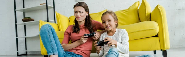 KYIV, UKRAINE - SEPTEMBER 4, 2019: panoramic shot of emotional babysitter and happy kid playing video game in living room — Stock Photo