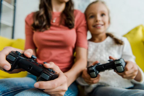 KYIV, UCRANIA - 4 de septiembre de 2019: enfoque selectivo de la niñera y el niño feliz jugando videojuegos en la sala de estar - foto de stock