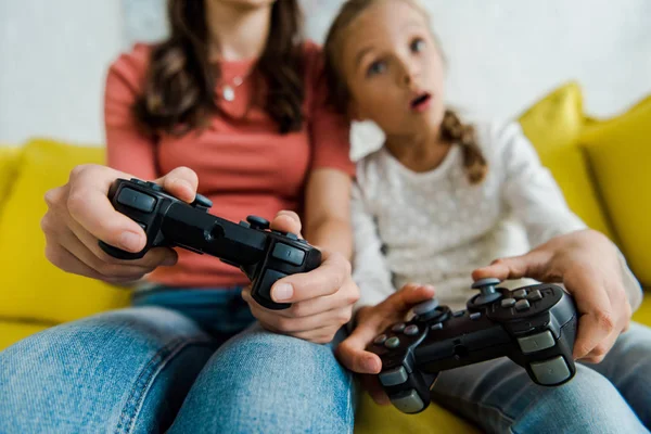 KYIV, UCRANIA - 4 de septiembre de 2019: enfoque selectivo de la niñera y el niño sorprendido jugando videojuegos en la sala de estar - foto de stock