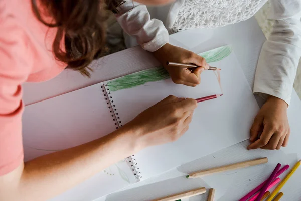 Vista recortada de la niñera dibujo con niño en la sala de estar - foto de stock