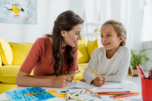 Happy babysitter looking at positive kid smiling in living room — Stock Photo