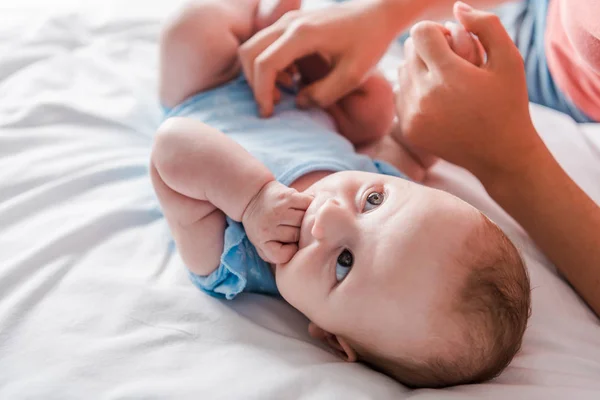 Corte vista de mãe segurando mão de bebê filha chupando dedos — Fotografia de Stock