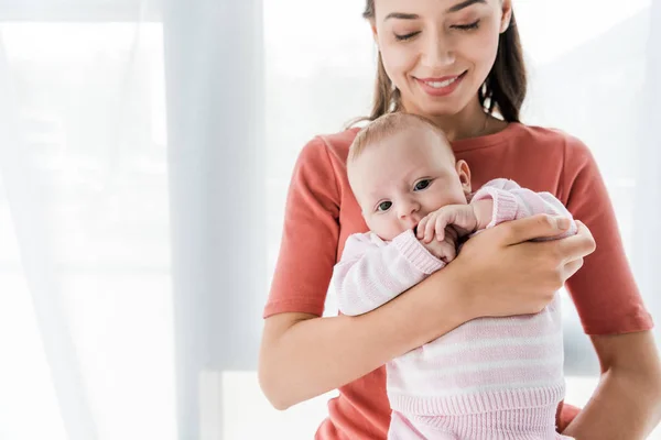 Smiling mother holding in arms adorable baby daughter — Stock Photo