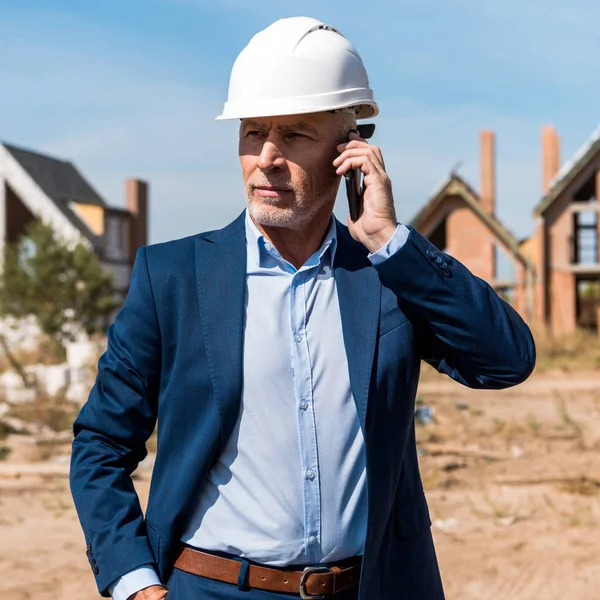 Mature bearded businessman in suit talking on smartphone — Stock Photo