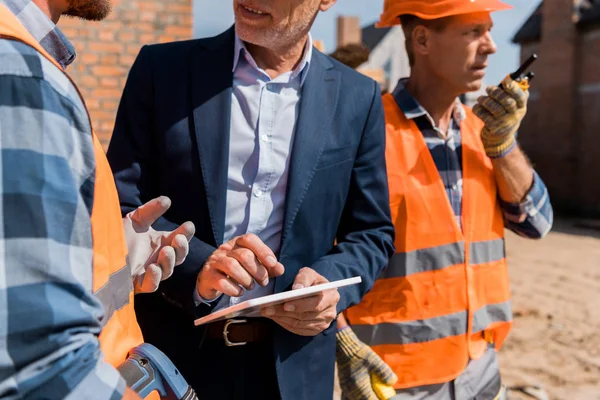 Cropped view of constructor gesturing near coworker and businessman with digital tablet — Stock Photo