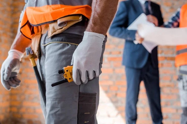 Cropped view of man holding walkie talkie near architect and coworker — Stock Photo