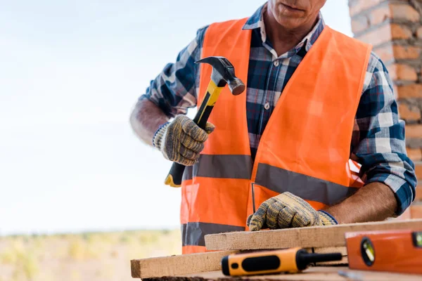 Vista recortada del constructor de mediana edad sosteniendo el martillo - foto de stock