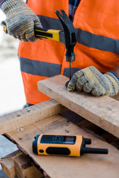 Vista recortada del constructor sosteniendo el martillo cerca de Hobnail - foto de stock