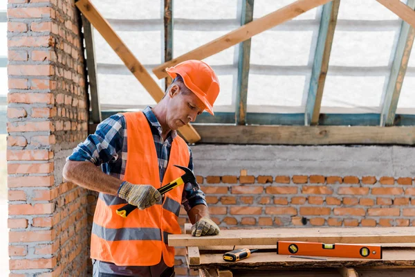 Construtor de idade média segurando martelo perto hobnail — Fotografia de Stock