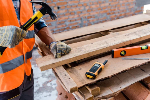 Vista recortada de constructor de mediana edad sosteniendo martillo cerca de Hobnail - foto de stock