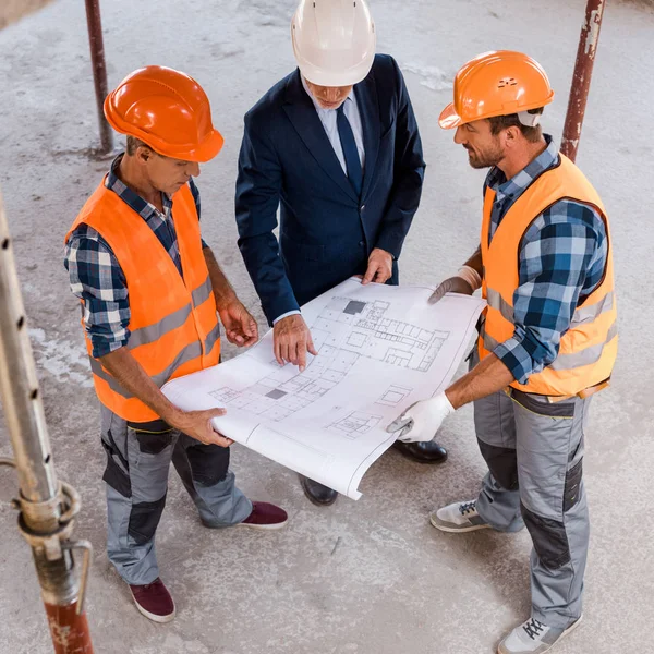 Vue aérienne des constructeurs et des hommes d'affaires tenant un plan directeur — Photo de stock