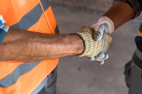 Vista recortada del constructor estrechando la mano con el arquitecto - foto de stock