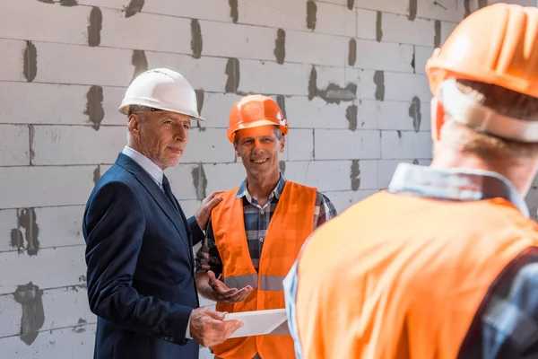 Foco seletivo do construtor e empresário olhando para o construtor — Fotografia de Stock