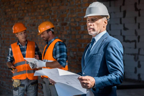 Selektiver Fokus von Geschäftsleuten, die Baupläne in der Nähe von Bauunternehmern halten — Stockfoto