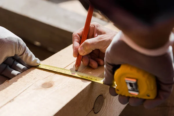 Cropped view of mature constructor holding pencil near measuring tape — Stock Photo