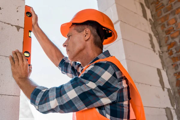 Mature architect in helmet measuring concrete wall — Stock Photo