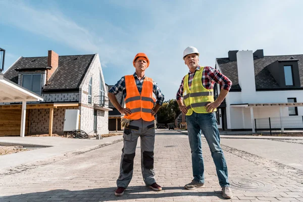 Constructores de mediana edad de pie con las manos en las caderas fuera - foto de stock