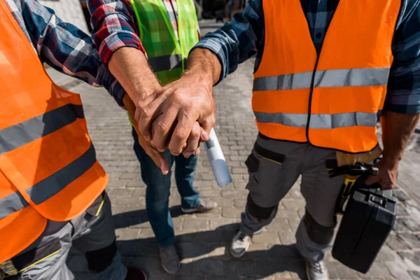 Vista cortada de construtores colocando as mãos juntas fora — Fotografia de Stock