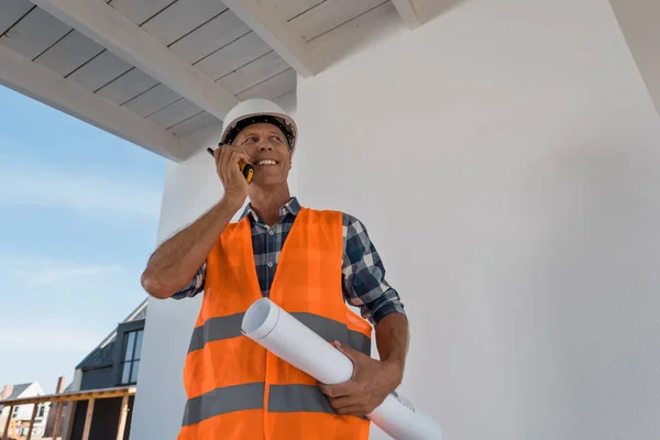 Happy mature man holding walkie talkie and blueprint — Stock Photo