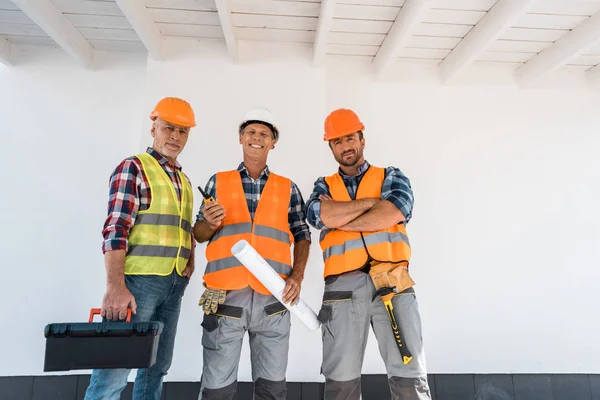 Happy constructors standing with blueprint and toolbox — Stock Photo