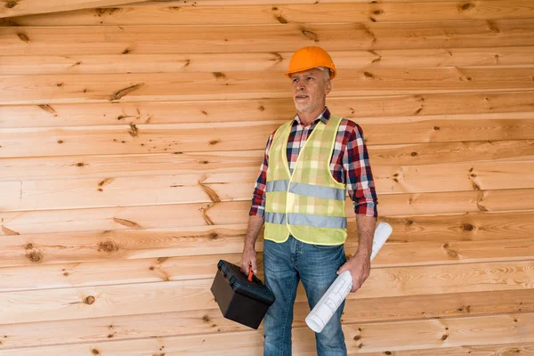 Barbudo hombre de mediana edad sosteniendo caja de herramientas y plano - foto de stock