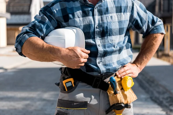 Cropped view of man holding helmet while standing with hand on hip — Stock Photo