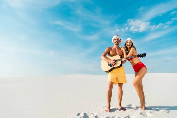 Sexy girlfriend and boyfriend playing acoustic guitar on beach in Maldives — Stock Photo