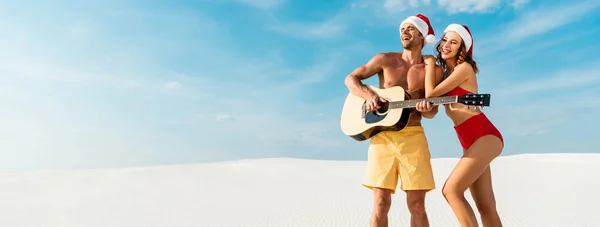 Plano panorámico de novia sexy y novio tocando la guitarra acústica en la playa en Maldivas - foto de stock