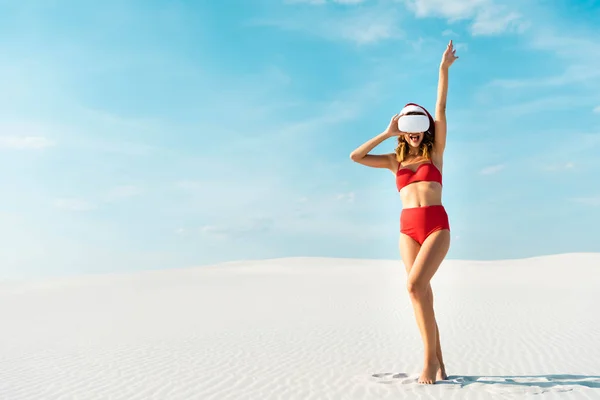 Sexy donna in cappello di Babbo Natale e costume da bagno con auricolare realtà virtuale sulla spiaggia in Maldive — Foto stock