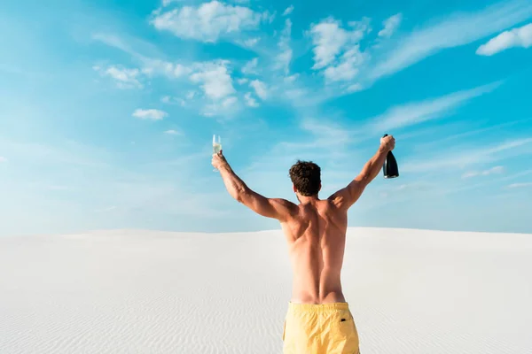 Back view de homem sexy segurando vidro e garrafa na praia em Maldivas — Fotografia de Stock