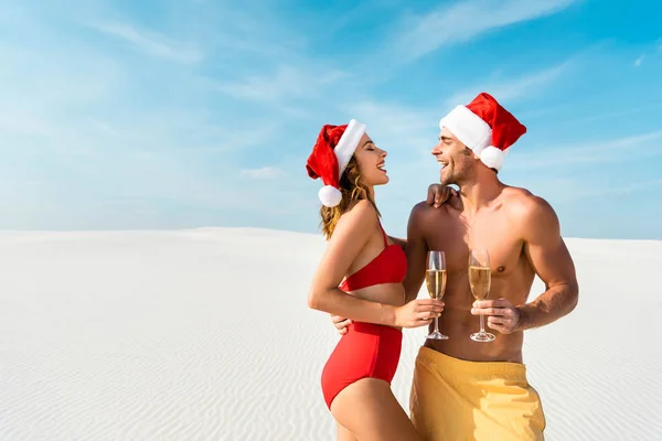 Sexy novia y novio sosteniendo copas de champán y abrazándose en la playa en Maldivas - foto de stock