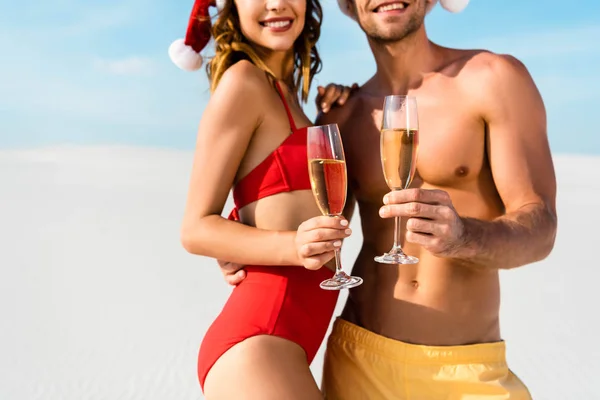 Крутий вид на сексуальну дівчину і хлопця, який тримає шампанські окуляри і обіймає пляж на Мальдівах. — стокове фото