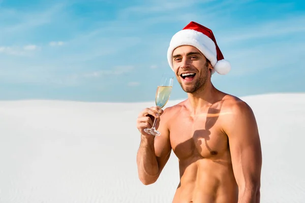 Sexy man in santa hat holding champagne glass on beach in Maldives — Stock Photo